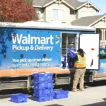 A man loading boxes into a walmart pickup and delivery truck.