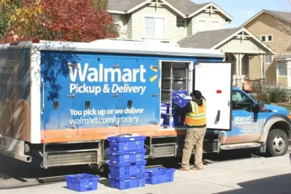 A man loading boxes into a walmart pickup and delivery truck.