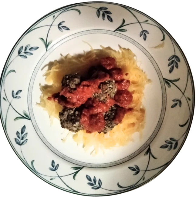 A photo of a plated meal consisting of Elk Pesto Meatballs with Spaghetti Squash and Tomato Sauce